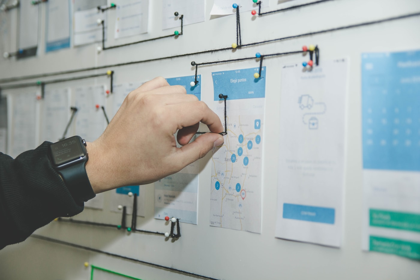 Hand pinning user flow wireframes on a planning wall